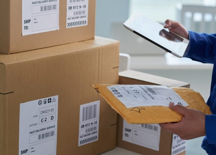 Close-up image of mail worker checking information on parcels